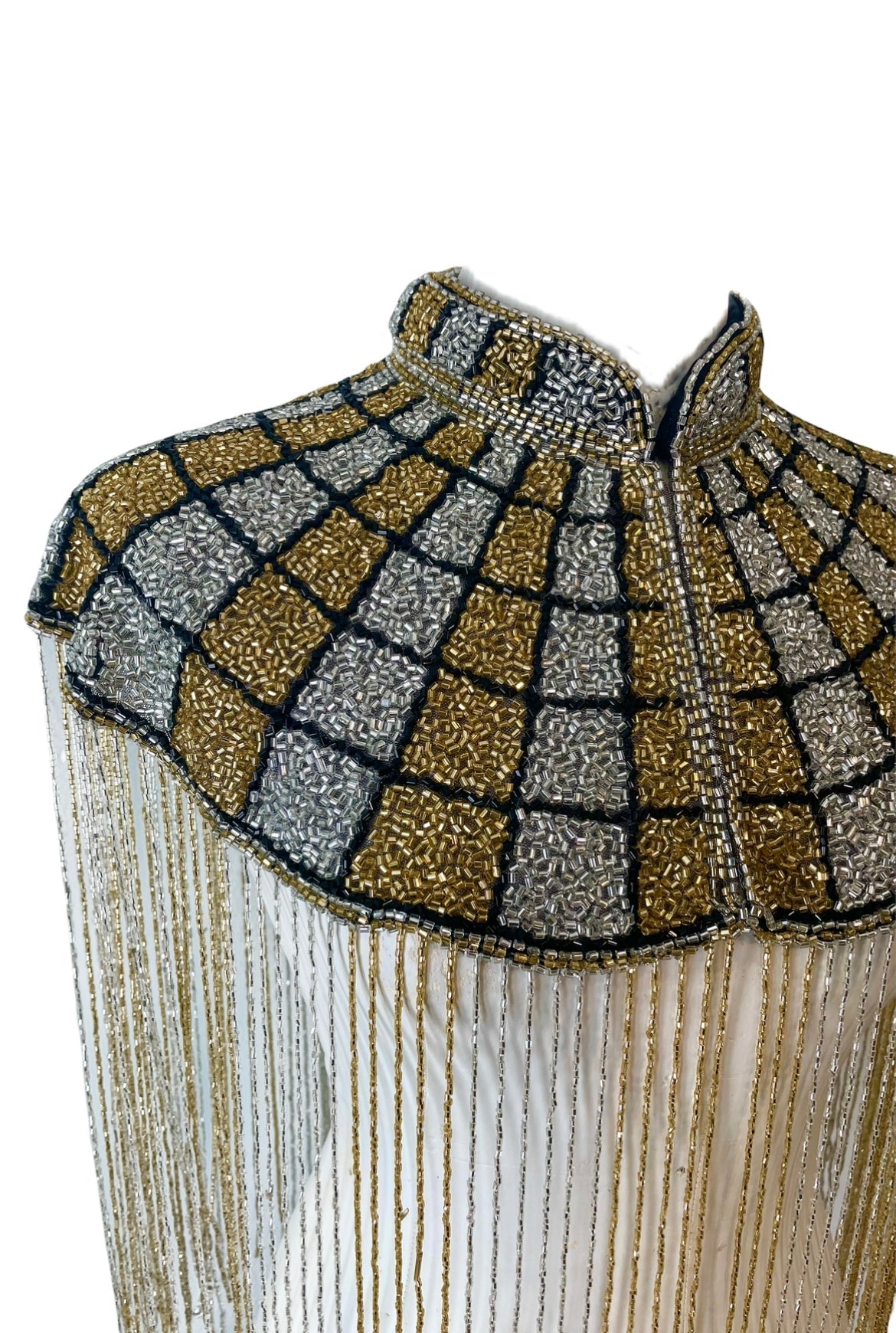 L'Jai Amor The Gilded Mosaic Cape displayed on a hanger, featuring intricate gold and mosaic patterns in luxurious fabric.