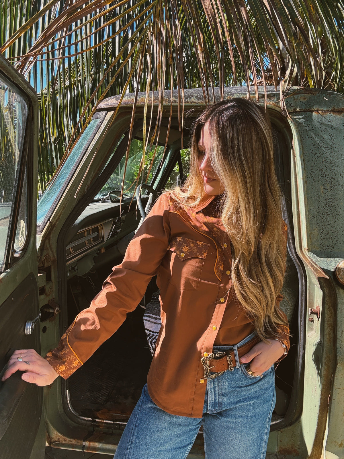 John Wayne Western pearl snap button-up top in brown by Lil Bee's Bohemian, shown on a hanger with detailed fabric and button close-up.