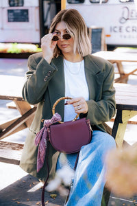 Burgundy semi-circle crossbody handbag by Margo Paige with adjustable strap and minimalist design.