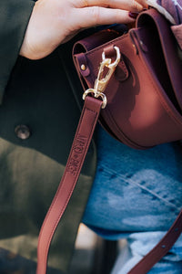Burgundy semi-circle Margo Paige handbag with adjustable strap and gold-tone hardware, stylish and compact crossbody bag.