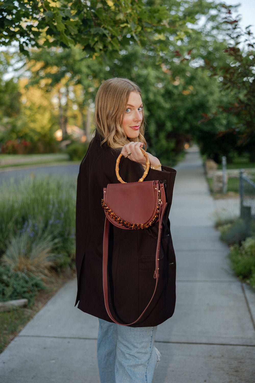 Burgundy semi-circle leather crossbody handbag by Margo Paige with adjustable strap and gold-tone hardware.