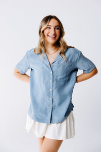 Margo Paige washable silk button-down shirt displayed on a hanger, showcasing smooth, shiny fabric and classic collar design.