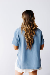Margo Paige washable silk button-down shirt displayed on a hanger, showcasing its smooth, lightweight fabric and classic collar style.
