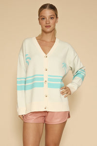 Miss Sparkling ocean sunset knit cardigan hanging on a wooden hanger, featuring a soft, colorful pattern and cozy design.