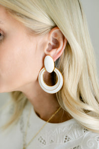 White enamel circle jewelry piece by Modafleur, close-up of smooth, glossy round enamel surface on a neutral background.