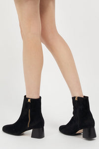 Black suede Arina ankle bootie with a block heel from Joan Oloff Shoes, featuring a sleek design and stylish silhouette.
