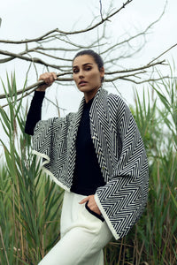 Soft knit shawl by profile-nyc, draped over a neutral background, showcasing its cozy texture and versatile style.