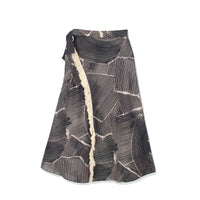 Faux wrap fringe skirt by profile-nyc featuring layered fringe details and a stylish wrap design, shown in a natural fabric.