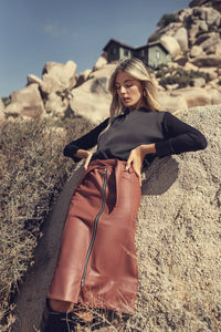 Black leather zipper skirt by Profile NYC, featuring a fitted design with a front zipper closure and sleek style.