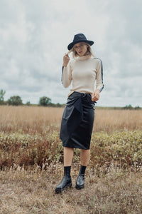 Black straight leather skirt with buckle detail by profile-nyc, shown on a model with a sleek, fitted silhouette.