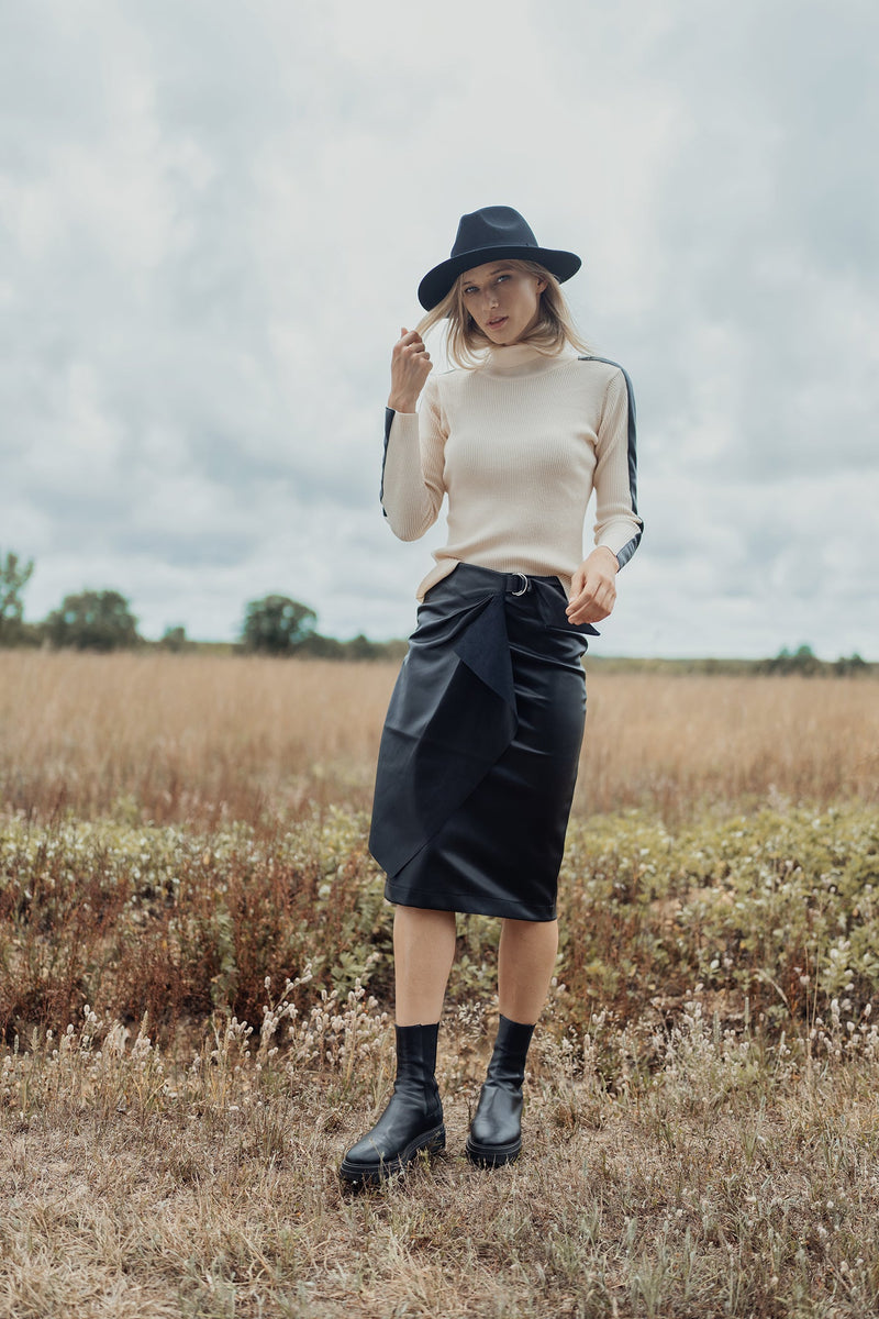 Black straight leather skirt with buckle detail by profile-nyc, shown on a model with a sleek, fitted silhouette.