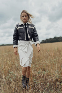 Black leather skirt with a buckle detail, straight fit, from Profile NYC, shown on a model with a stylish urban background.