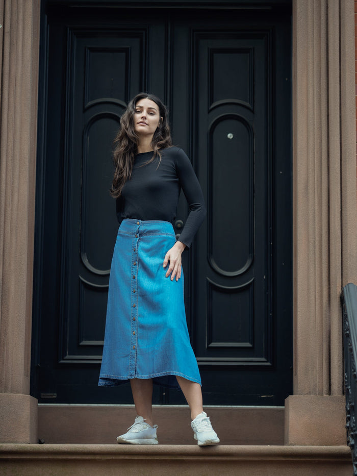 Soft denim button skirt by Profile NYC, showing a stylish A-line design with front buttons and a casual, versatile look.
