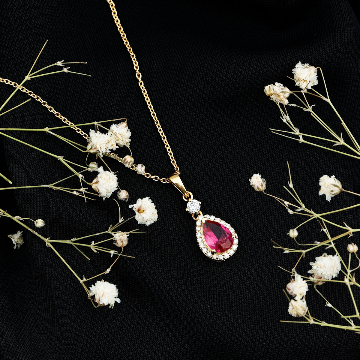 Lab-created ruby teardrop pendant with moissanite halo, elegant jewelry piece showcasing a vibrant ruby and sparkling stones.