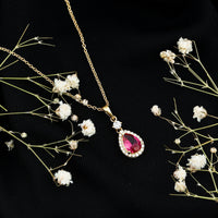 Lab-created ruby teardrop pendant with moissanite halo, elegant jewelry piece showcasing a vibrant ruby and sparkling stones.