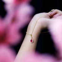 Lab-created ruby teardrop pendant with moissanite halo by Rosec Jewels, featuring a sparkling gemstone necklace.