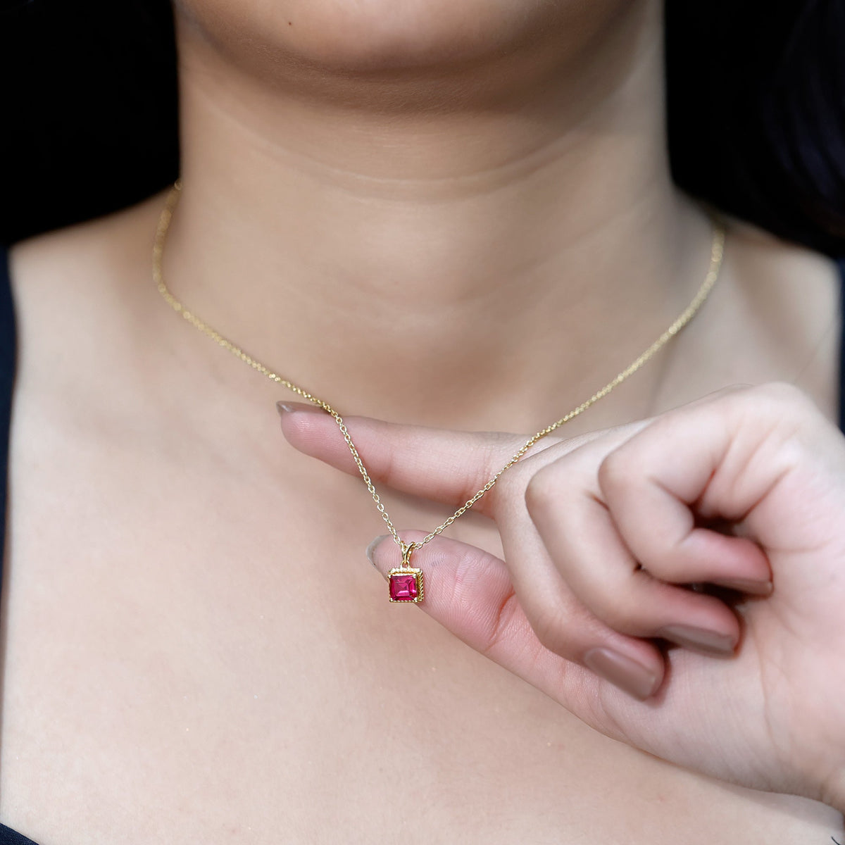 Princess cut lab-created ruby solitaire pendant with rope frame, showcasing a sparkling red gemstone set in a delicate pendant.