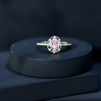 Natural pink sapphire and diamond vintage engagement ring in silver featuring intricate detailing and a elegant design.