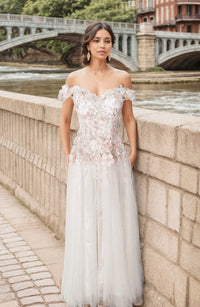Rubi off-the-shoulder apricot pink floral lace prom dress with A-line tulle skirt, styled for a wedding or special occasion.