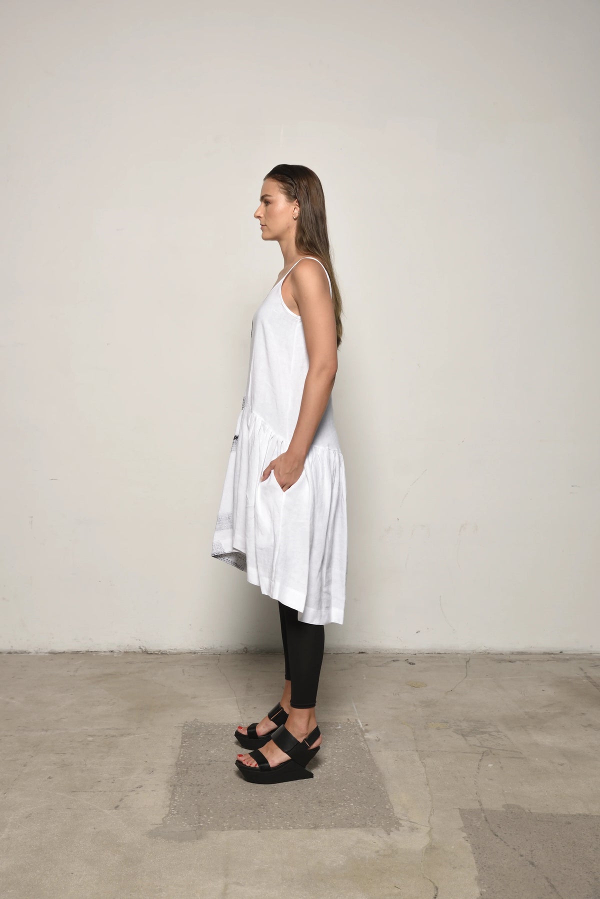White linen peplum dress by SIMPLY MILA, side view showcasing fitted waist and flowing skirt for modern women's fashion.
