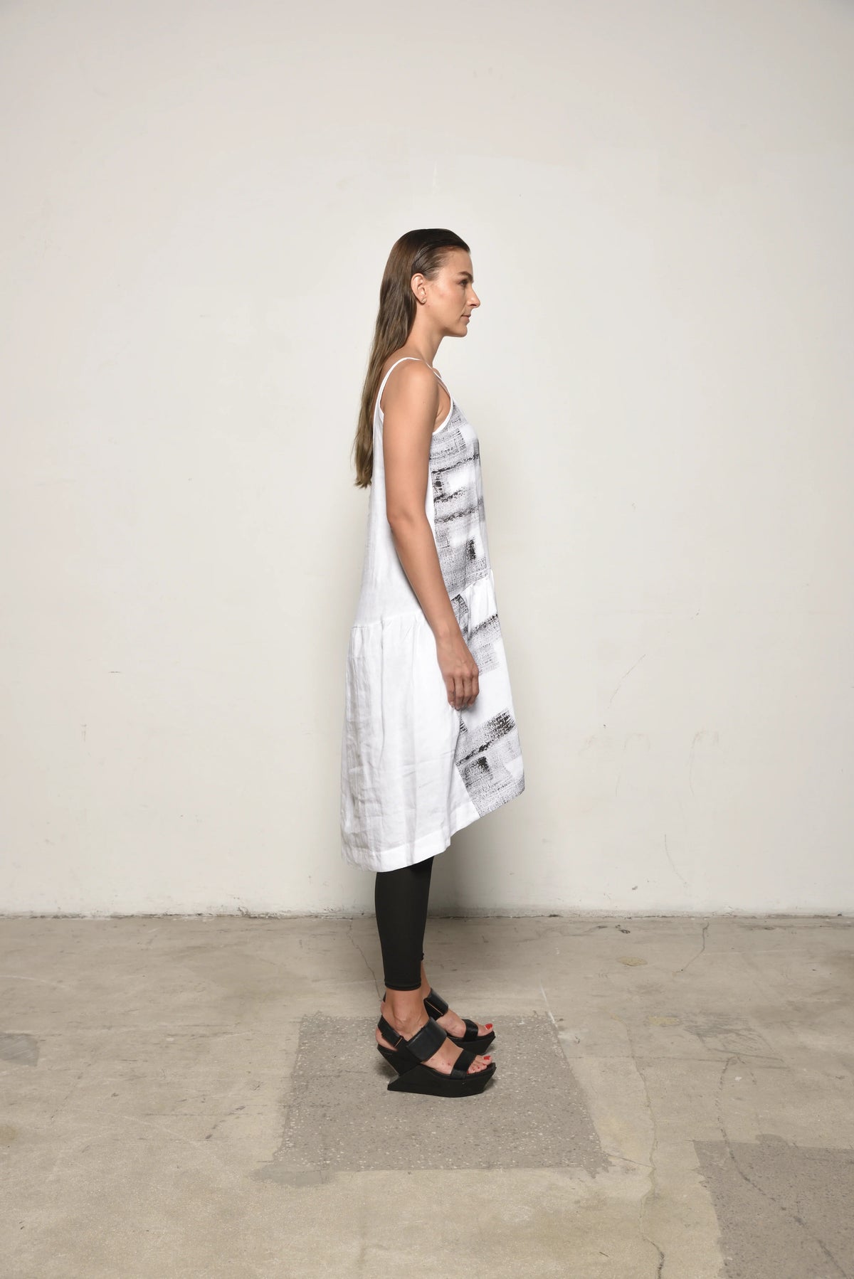 White linen peplum dress by SIMPLY MILA, side view showing fitted waist, flared skirt, and sleeveless design.
