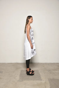 White linen peplum dress by SIMPLY MILA, side view showing fitted waist, flared skirt, and sleeveless design.