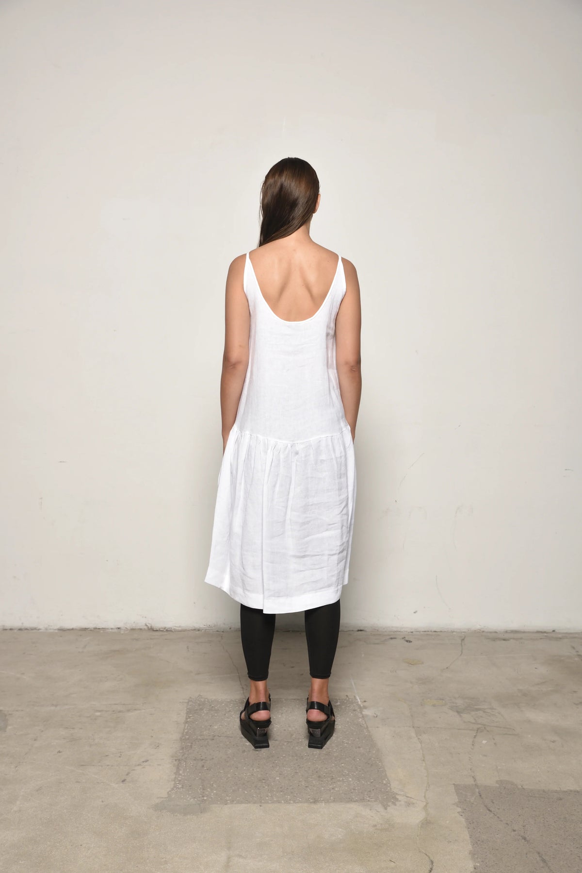 Back view of a white linen peplum dress by SIMPLY MILA, featuring a fitted bodice and flared peplum hem for a stylish look.
