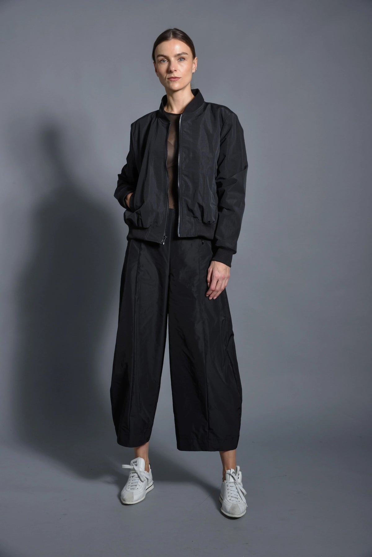 Black SIMPLY MILA modern women's baseball jacket with contrasting sleeves and snap buttons, displayed on a hanger.