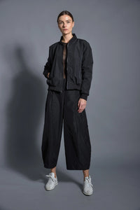 Black SIMPLY MILA modern women's baseball jacket with contrasting sleeves and snap buttons, displayed on a hanger.