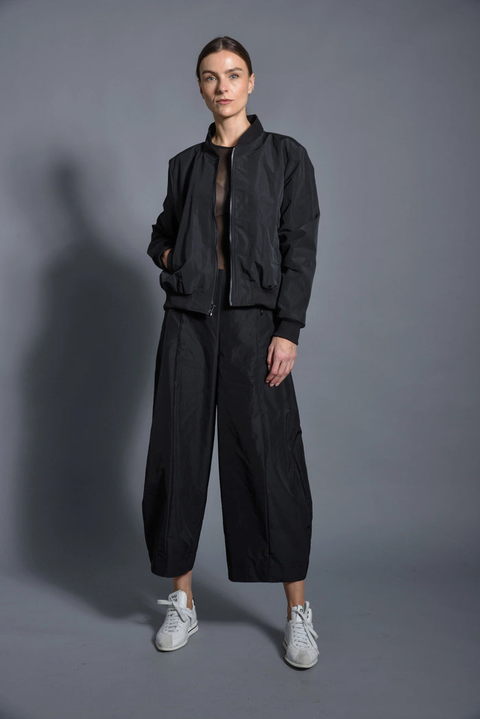 Black SIMPLY MILA modern women's baseball jacket with contrasting sleeves and snap buttons, displayed on a hanger.