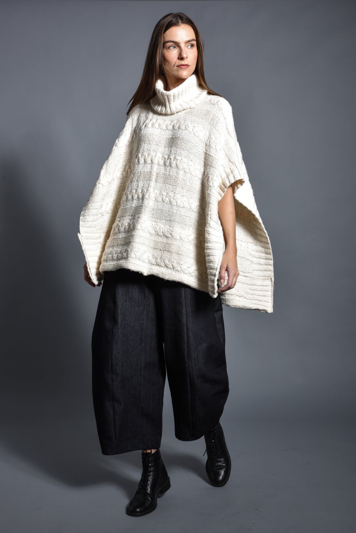 SIMPLY MILA modern women's cable poncho draped over a model, showcasing cozy, stylish knitwear for fall and winter wear.