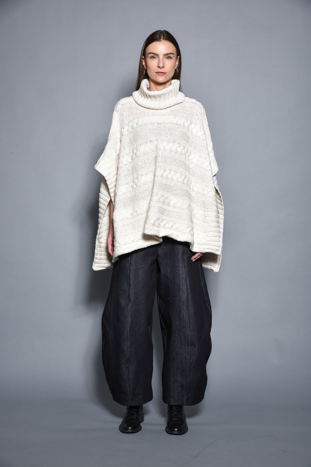 Gray cable-knit poncho by SIMPLY MILA, modern women's clothing, draped over a mannequin, showcasing cozy, stylish winter wear.