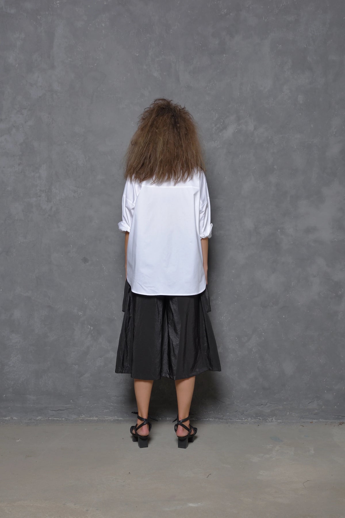Back view of a black Stroke Boxy Shirt for women by SIMPLY MILA, featuring a relaxed fit and modern design.
