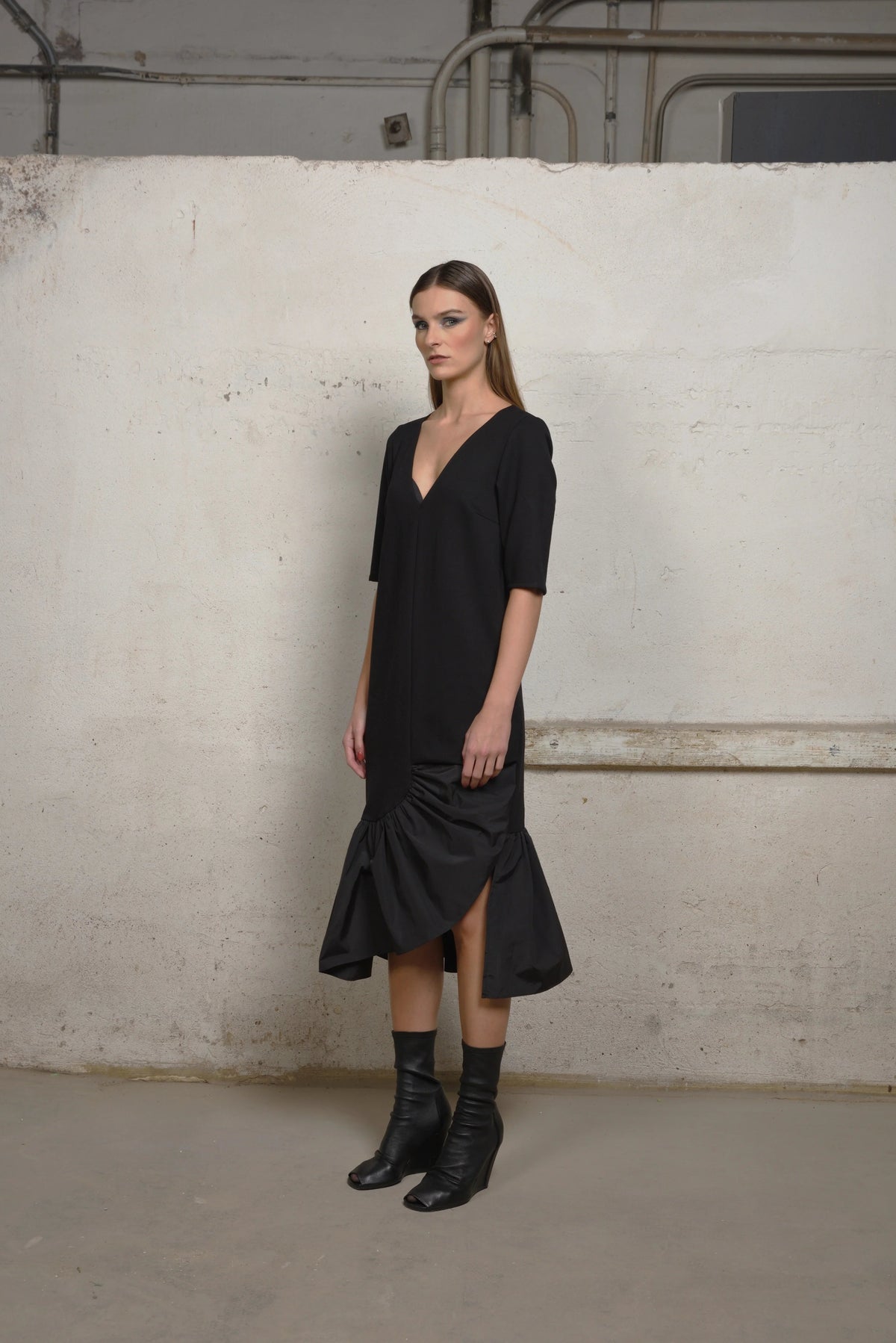 Side view of a SIMPLY MILA modern women's ruffle sweater dress with an unbalanced ruffle design, showcasing stylish knit fabric.