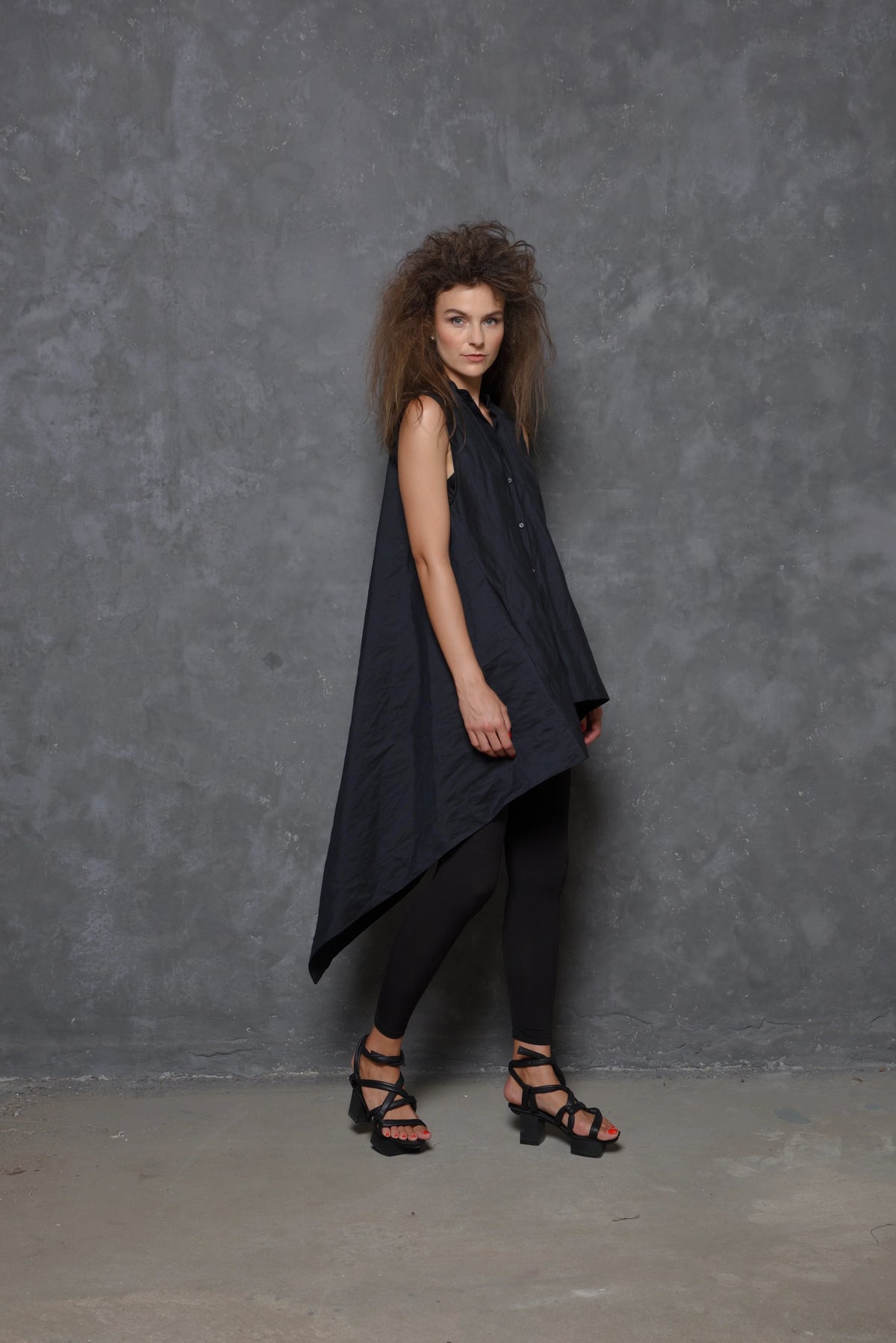 Sleeveless asymmetrical tunic shirt by SIMPLY MILA, displayed in a modern women's clothing style with flowing fabric.