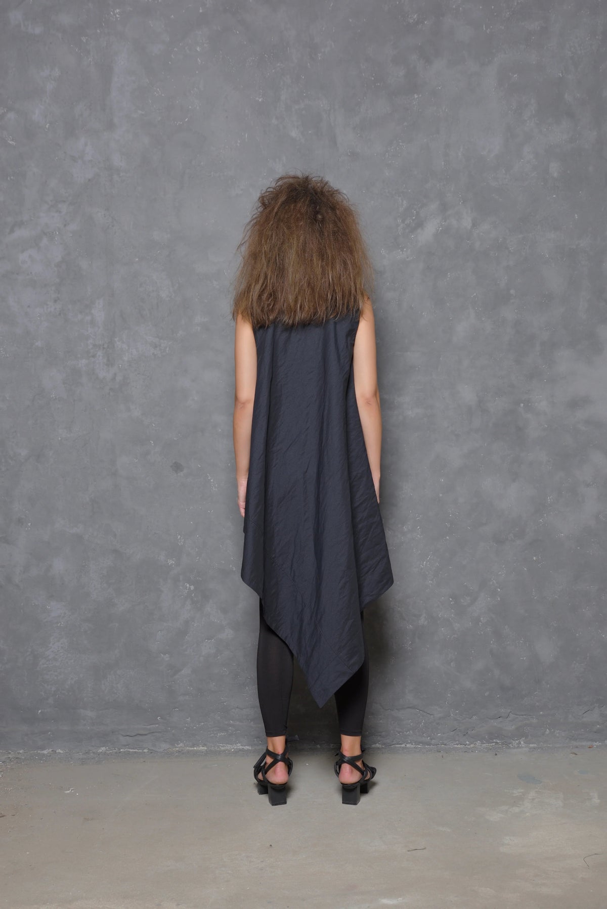 Sleeveless asymmetrical tunic shirt from SIMPLY MILA, featuring a modern design with flowing fabric and unique hemline.