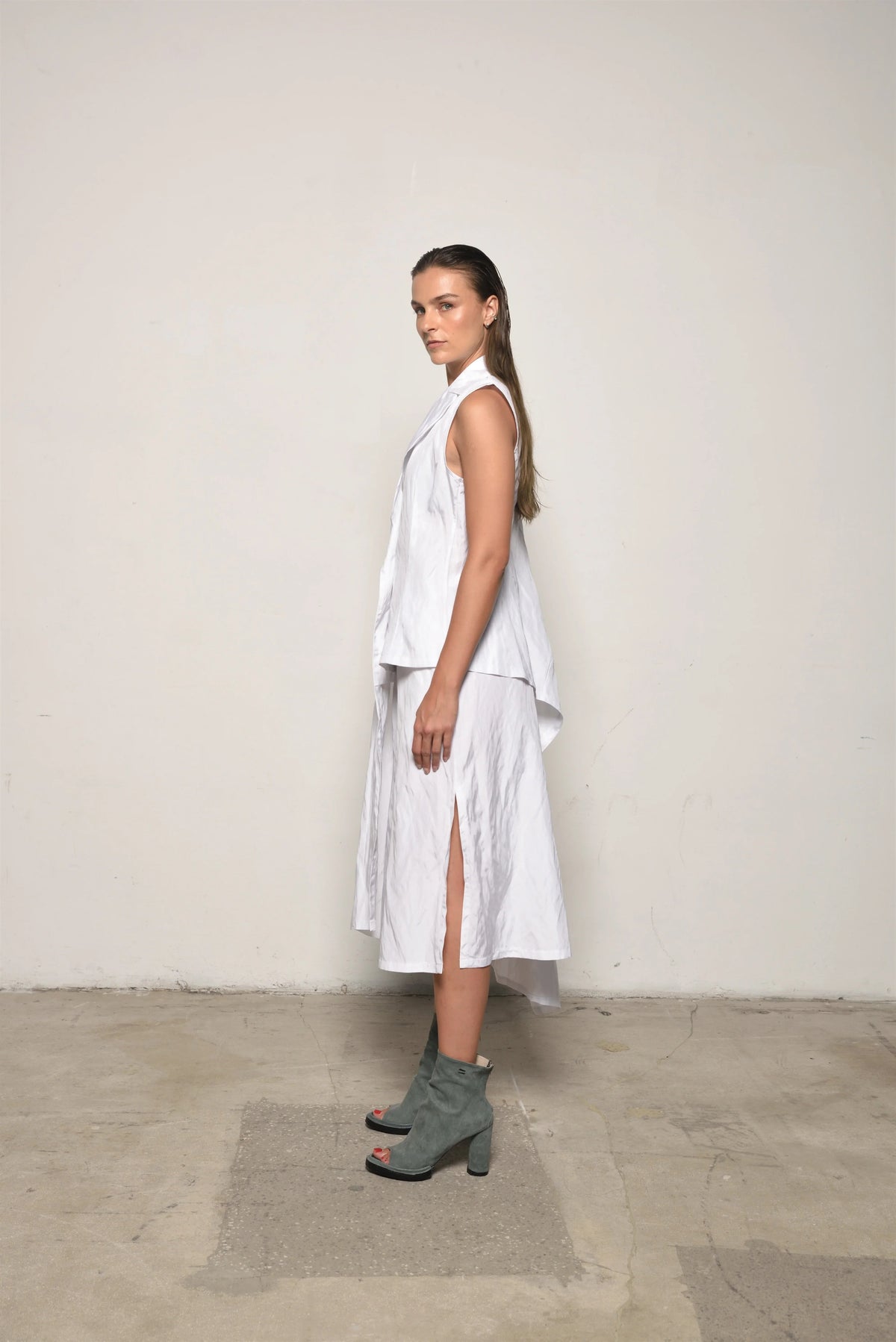 White uneven vest by SIMPLY MILA Modern Women's Clothing, side view showcasing textured fabric and stylish asymmetric design.