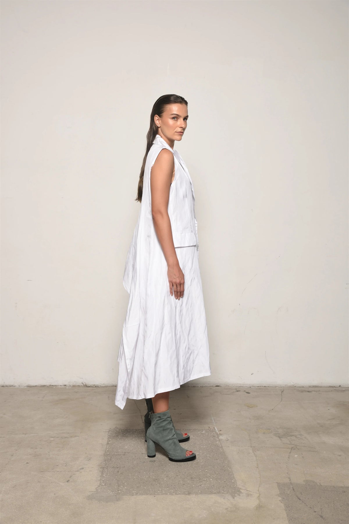 Side view of a white uneven vest by SIMPLY MILA Modern Women's Clothing, showcasing its unique asymmetrical design.