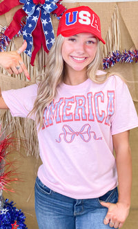 America Frilly Bow Graphic T-Shirt by Sugar Stitch Wholesale featuring a colorful bow graphic on a casual T-shirt.