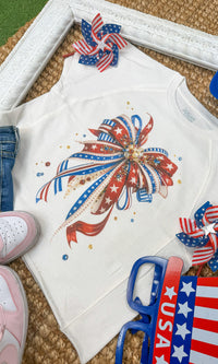 Close-up of a patriotic ribbon bow graphic on a Sugar Stitch Wholesale edgy graphic shirt, showcasing bold red, white, and blue design elements.