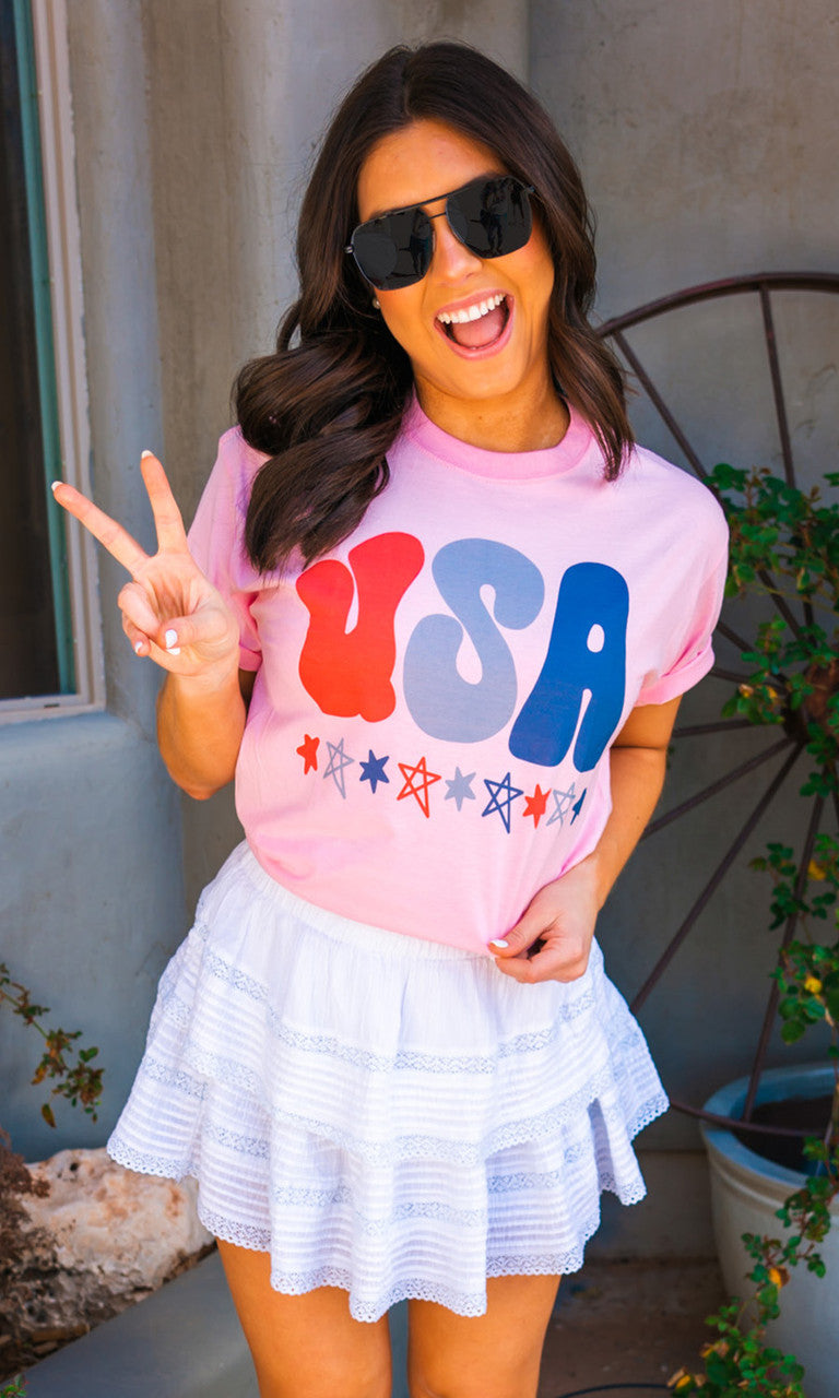 Pink USA graphic T-shirt by Sugar Stitch Wholesale featuring a patriotic design on soft cotton fabric.