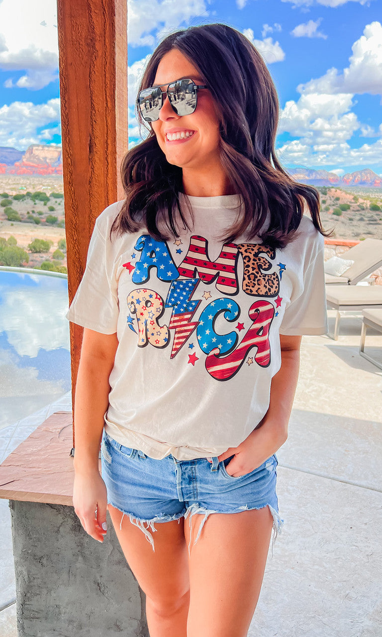 Front view of a Sugar Stitch Wholesale Retro America graphic T-shirt featuring vintage-inspired USA flag and retro design.
