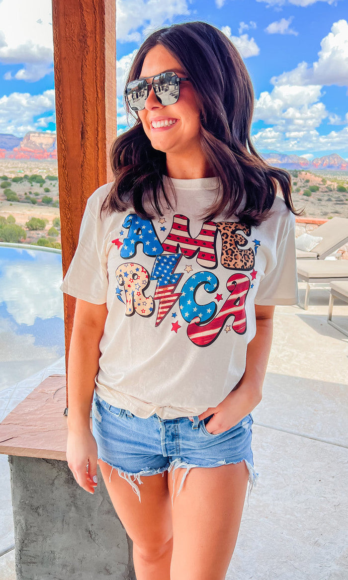 Front view of a Sugar Stitch Wholesale Retro America graphic T-shirt featuring vintage-inspired USA flag and retro design.