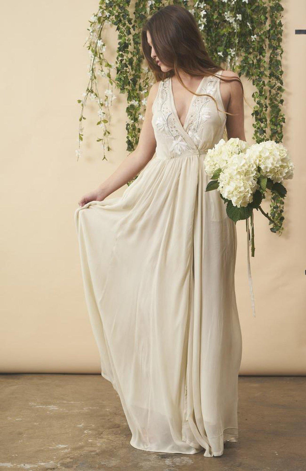 Cream floral embroidered wedding dress by SymbologyClothing featuring silver accents and intricate embroidery on a flowing fabric.