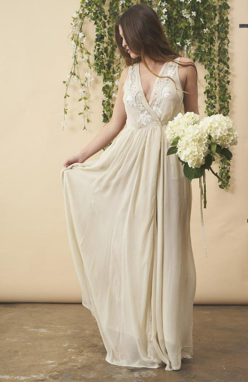 Cream floral embroidered wedding dress by SymbologyClothing featuring silver accents and intricate embroidery on a flowing fabric.