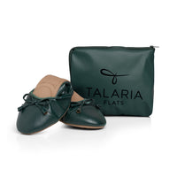 Green Talaria Flats shoes folded in front of a bag, showcasing the premium evergreen slip-on shoes for women.