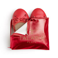 Talaria Flats premium ruby red flats inside a stylish bag, showcasing elegant slip-on shoes with a vibrant red color.