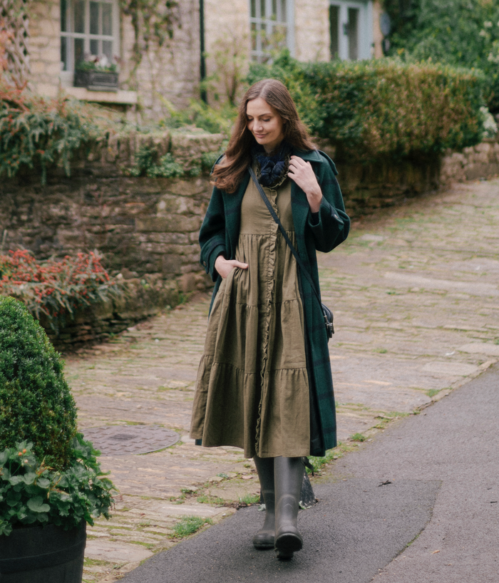 The Village Green house dress displayed on a hanger, featuring a relaxed fit with floral pattern and soft fabric for comfortable wear.