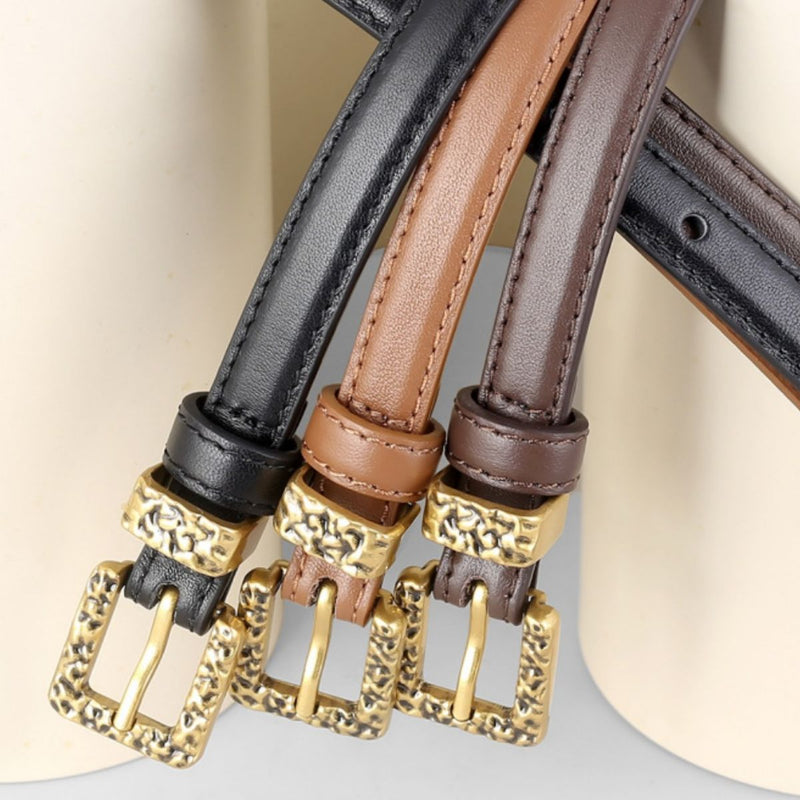 Black skinny leather belt with metal buckle from Trendsi, displayed rolled up showing smooth leather and shiny hardware.