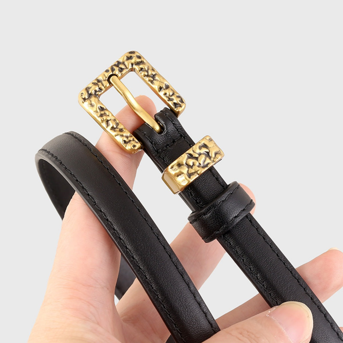 Black skinny leather belt with silver buckle from Trendsi, featuring sleek design and adjustable strap for a chic, modern look.